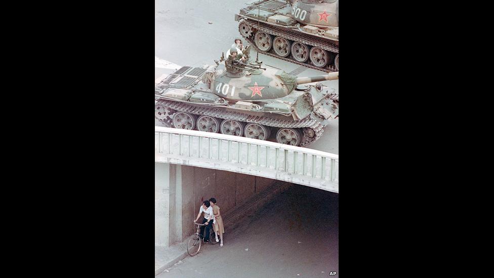 A Chinese couple on a bicycle take cover as tanks move overhead in Beijing on 5 June 1989