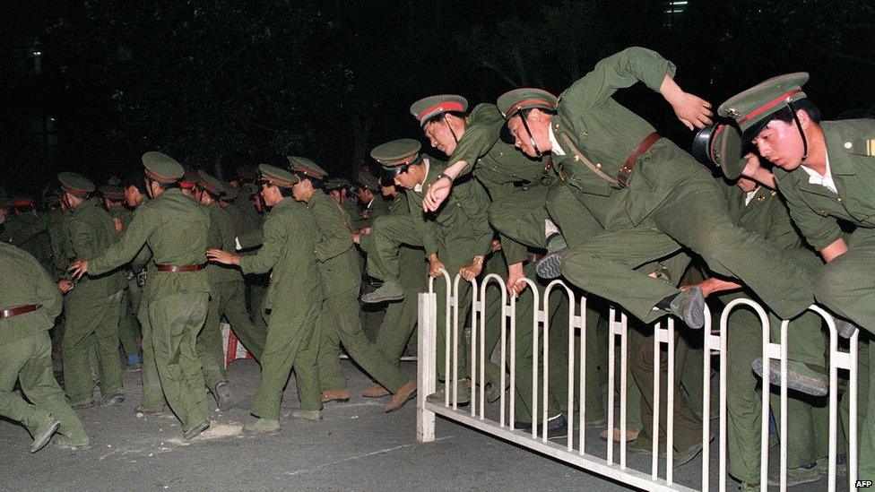 People Liberation Army soldiers leap over a barrier at Tiananmen Square in central Beijing on 4 June 1989