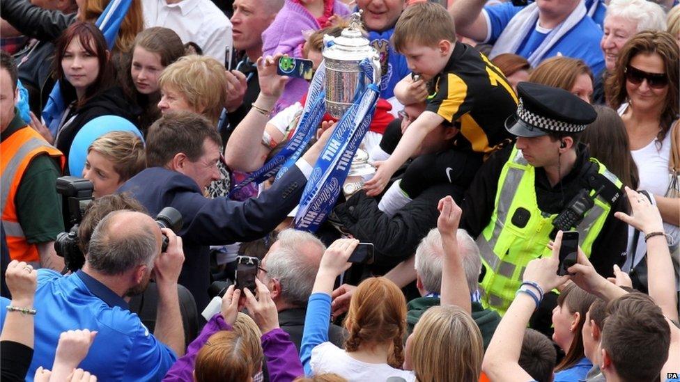 A young fan touches the Scottish Cup held by St Johnstone manager Tommy Wright as he makes his way through the crowds