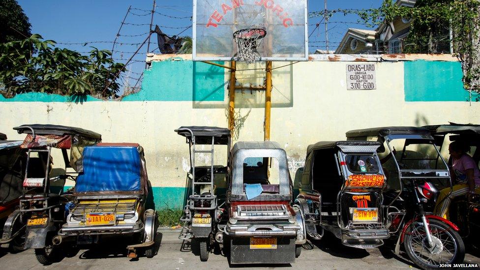 A basketball court by an alley that also serves as a dock for tricycles waiting for passengers during the day in Rizal, Philippines.