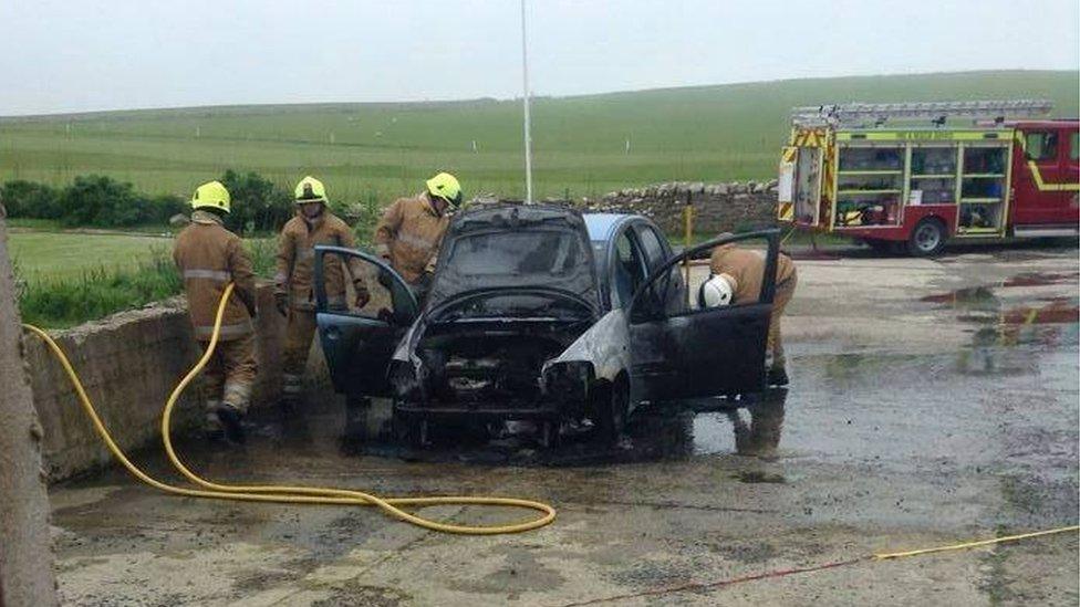 Firefighters at fire damaged car