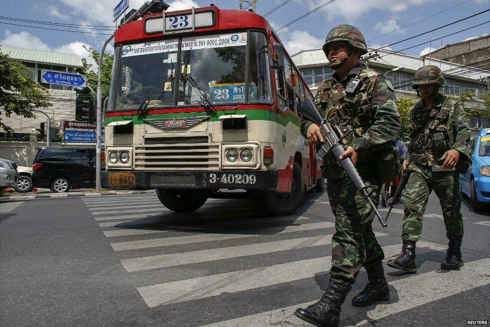 A bus passes Thai soldiers on patrol on a road near the Bangkok Army Club - 23 May 2014