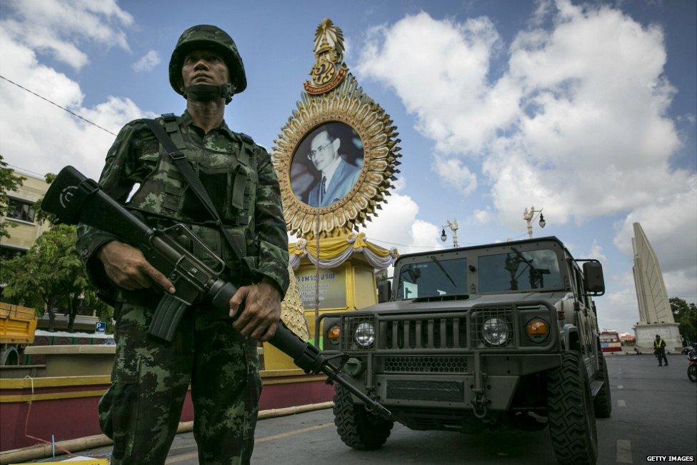 A Thai soldier stands in front of a portrait of Thai King Bhumibol Adulyadej as he patrols near government buildings in Bangkok - 23 May 2014