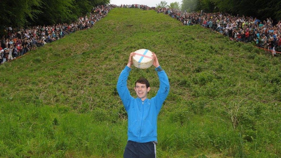 Josh Shepherd holding up a wheel of cheese.