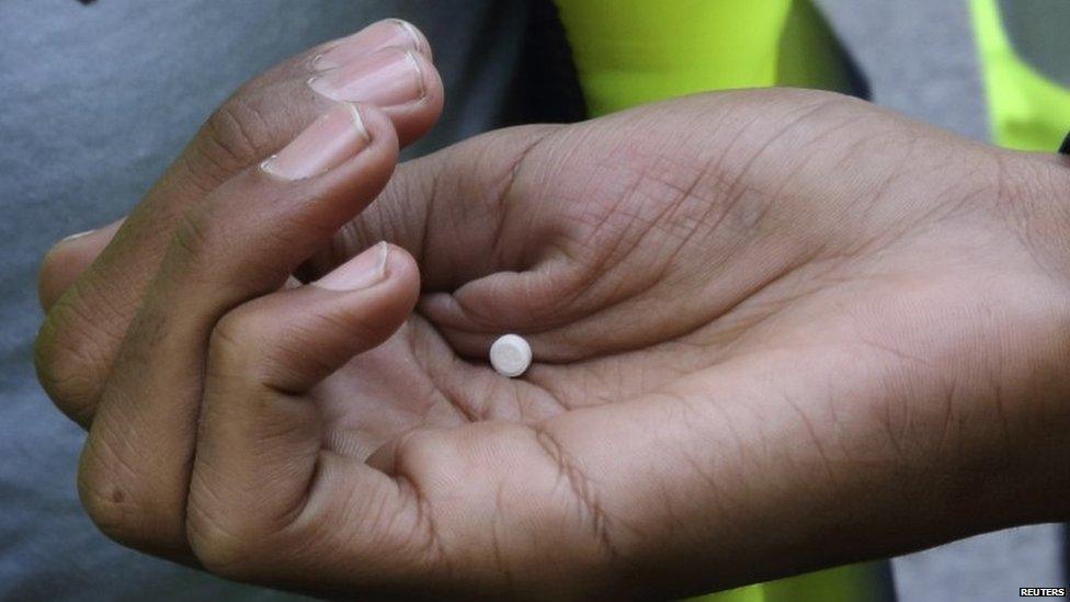 An African migrant holds medicine against scabies during the daily food distribution at the harbour in Calais