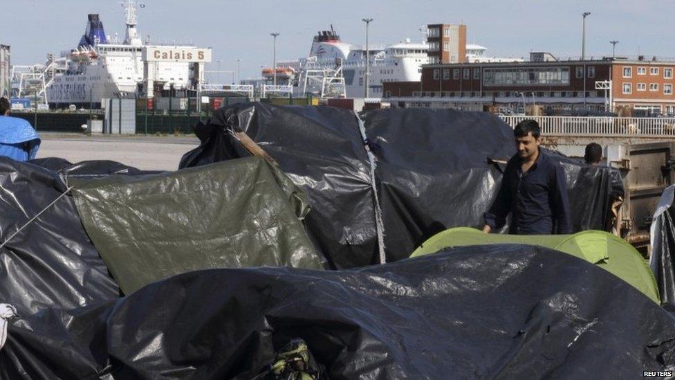 A migrant through a camp of makeshift shelters at the harbour in Calais