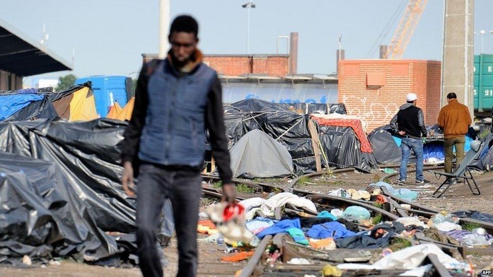 A man walks through a makeshift camp set up by migrants in Calais