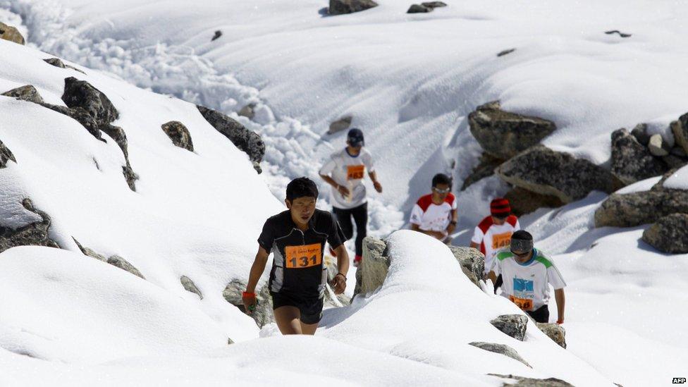 Men make their way through the snowy and rocky terrain of the course.