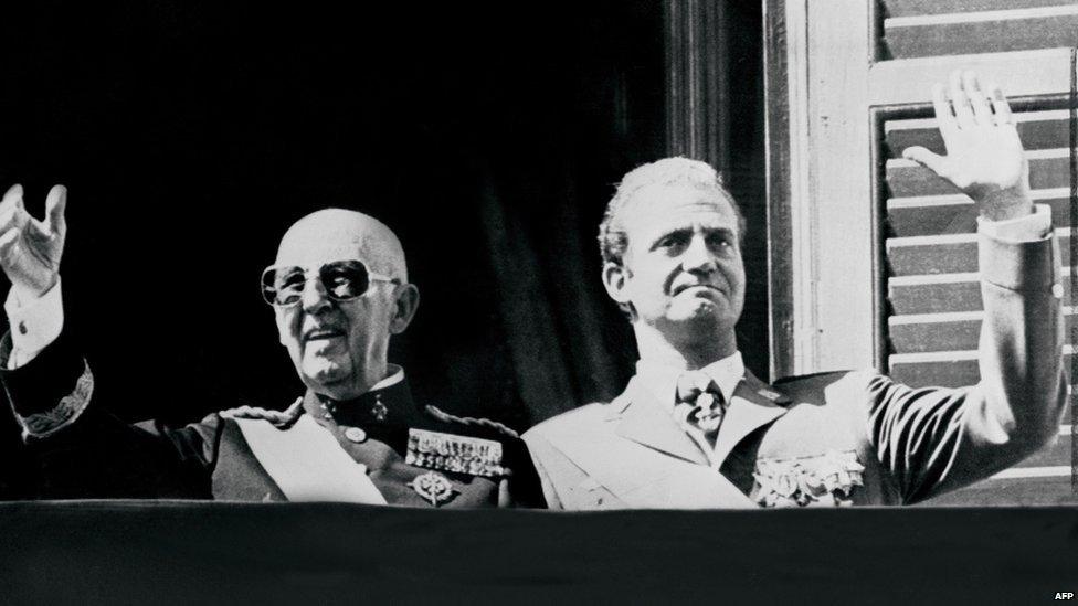 A file photo taken in October 1975 shows then Spanish head of state General Francisco Franco (L) and the then Prince Juan Carlos saluting the crowd in Madrid.