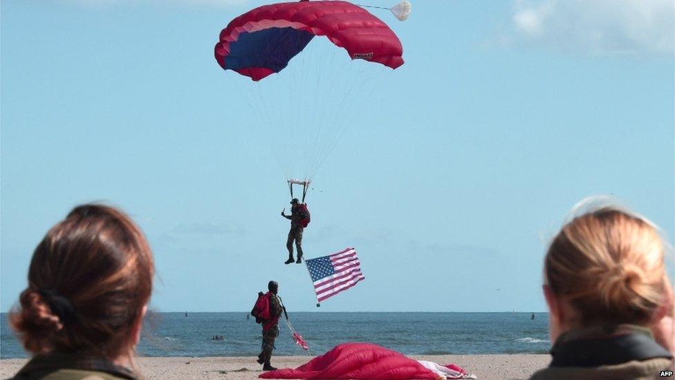 A French paratrooper carrying a US flag landed on Sword beach in Ouistreham