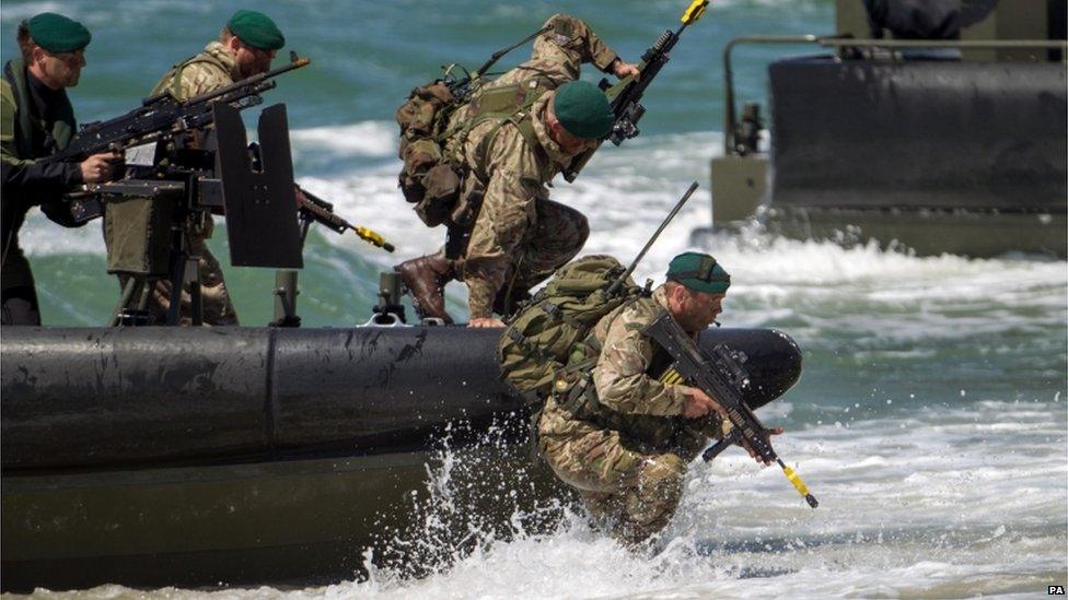 Troops jumping off a boat on to a beach