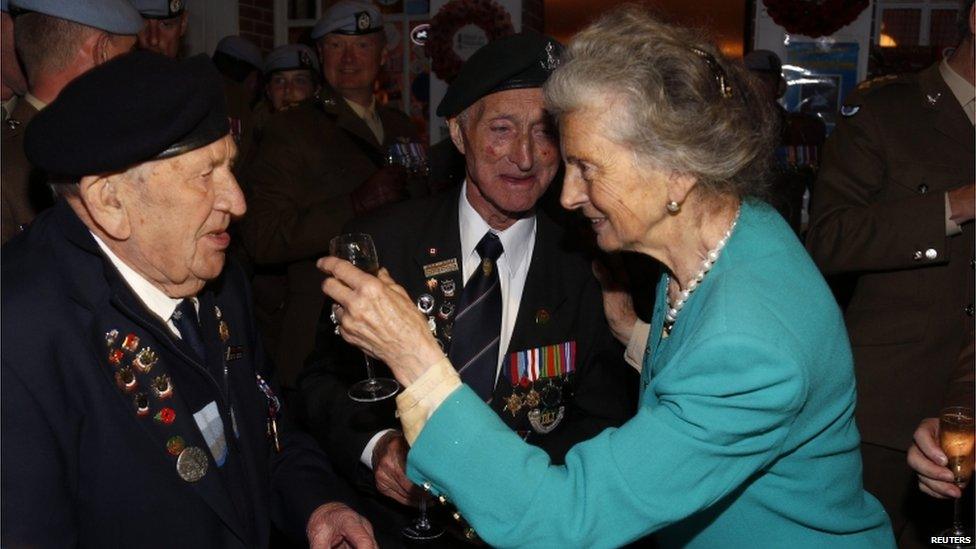 A woman raises a glass to two UK veterans