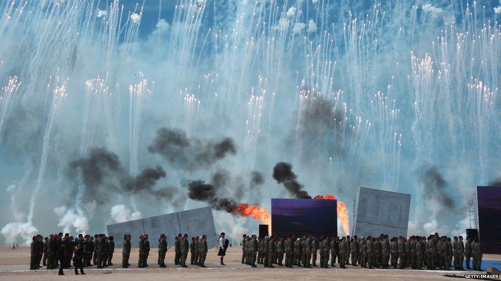 People perform as fireworks burst in the sky on the beach of Ouistreham, Normandy