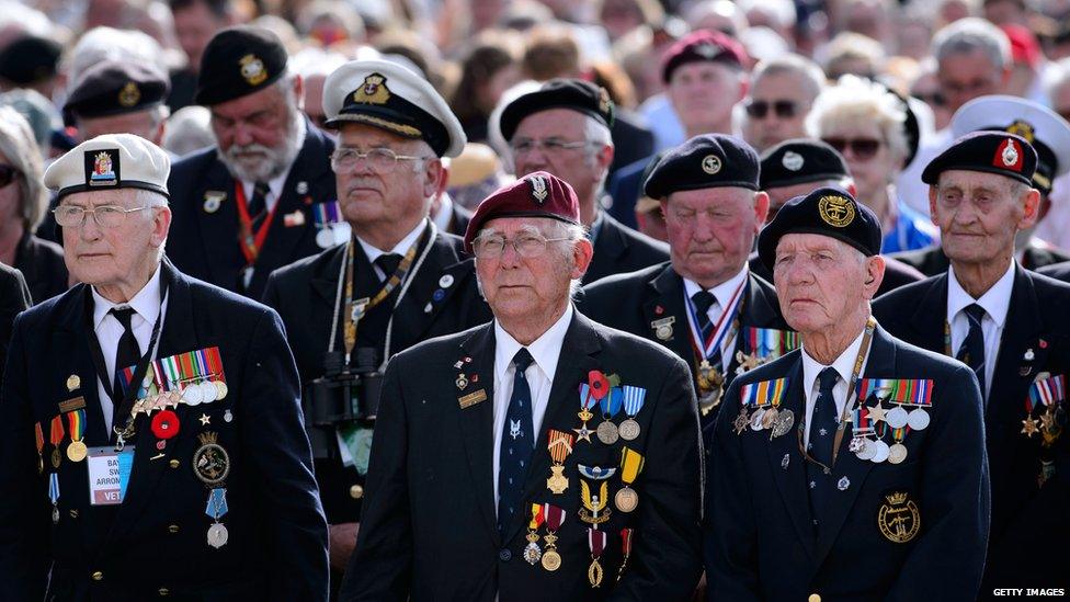 Veterans listen to a reading at a service in Arromanches-les-Bains