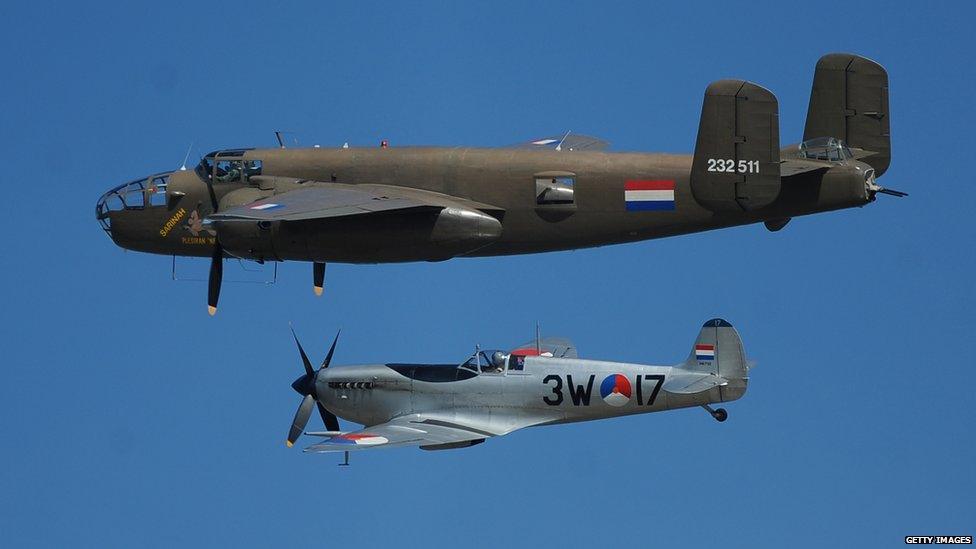 A Dutch B-25 Mitchell and a Spitfire fly over Arromanches-les-Bains