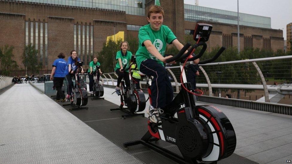 Lambeth school children ride static bikes on the Millennium Bridge