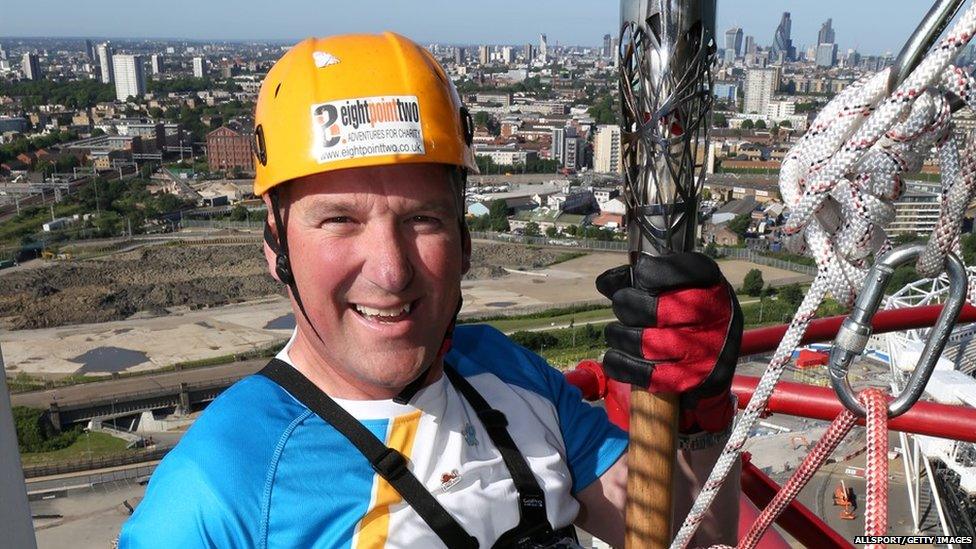 Sir Matthew Pinsent CBE holds the Queens Baton as he abseils down the Orbit tower at the Queen Elizabeth Olympic Park