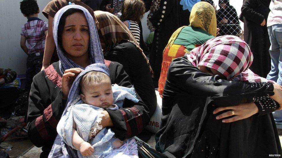 Families fleeing the violence in the Iraqi city of Mosul wait at a checkpoint on the outskirts of Erbil, on 10 June 2014.