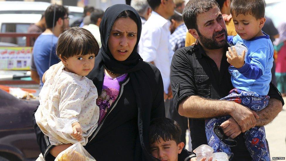 A family fleeing the violence in the Iraqi city of Mosul waits at a checkpoint near Irbil, in Iraq's Kurdistan region, 10 June 2014