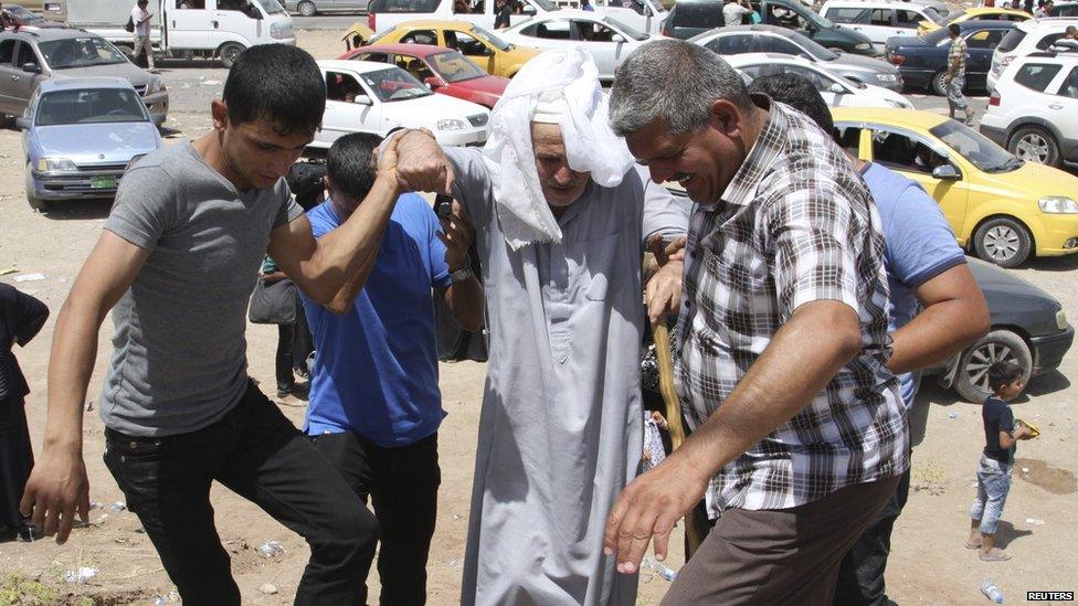 An elderly man is assisted at a checkpoint on the outskirts of Erbil on 10 June 2014.