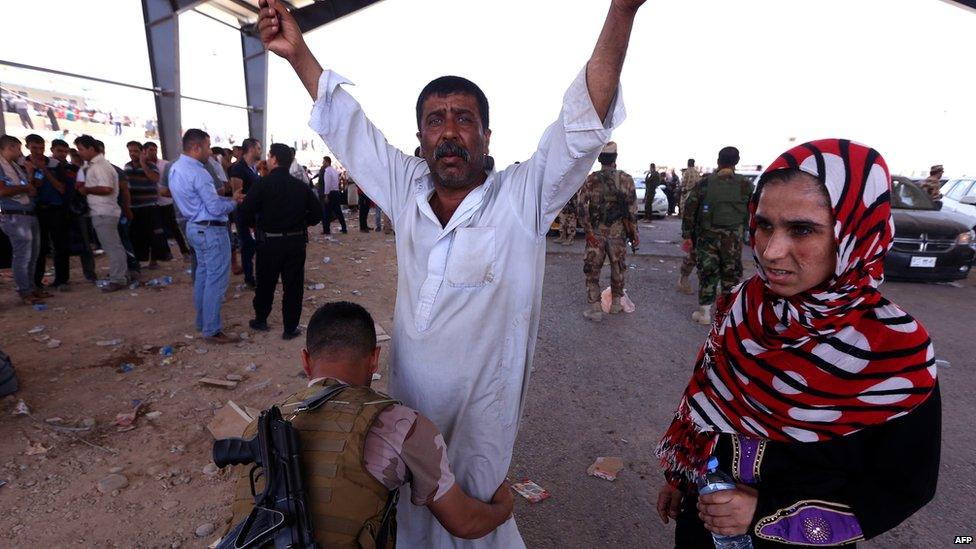 An Iraqi Kurdish security guard frisks a man as he waits at a checkpoint