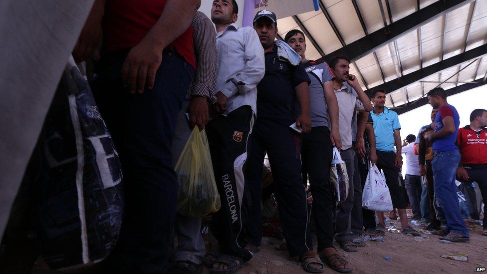 Iraqi men queue at a Kurdish checkpoint west of Erbil, on 10 June 2014