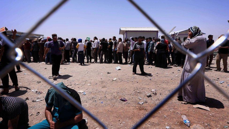 Iraqi families fleeing violence in the northern Nineveh province gather at a Kurdish checkpoint west of Erbil, on 10 June 2014