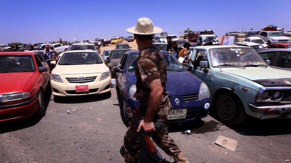 Iraqis fleeing violence in the Nineveh province wait in their vehicles at checkpoint west of Erbil, on 10 June 2014.