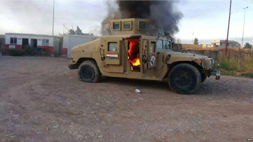 A picture taken with a mobile phone shows an armoured vehicle belonging to Iraqi security forces in flames on 10 June 2014, after hundreds of militants from the Islamic State of Iraq and the Levant (ISIS) launched a major assault on the security forces in Mosul