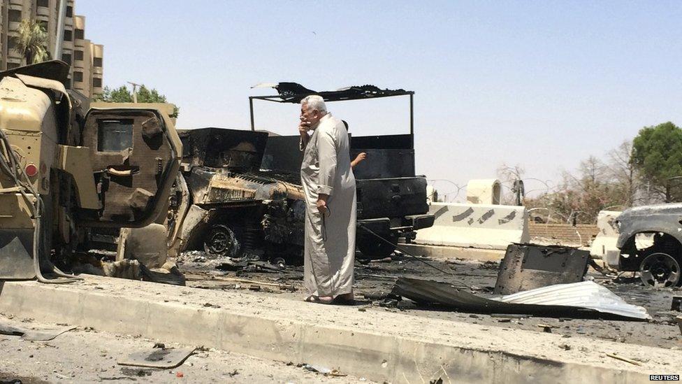 A man looks at burnt vehicles belonging to Iraqi security forces one day after insurgents seized control of the city of Mosul on 11 June 2014.