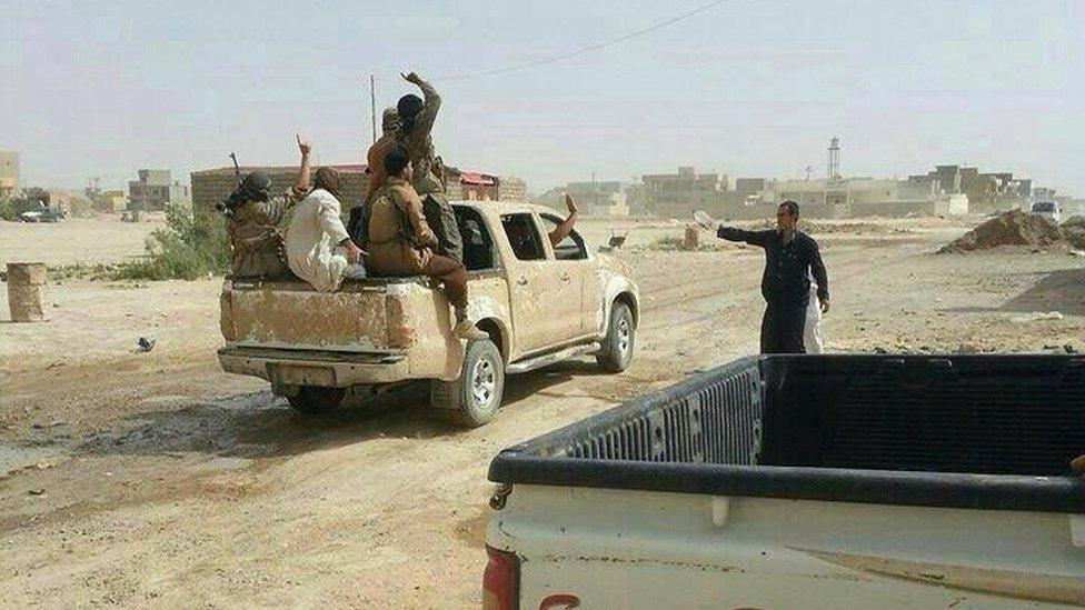 Militants gesture as they drive through Tikrit