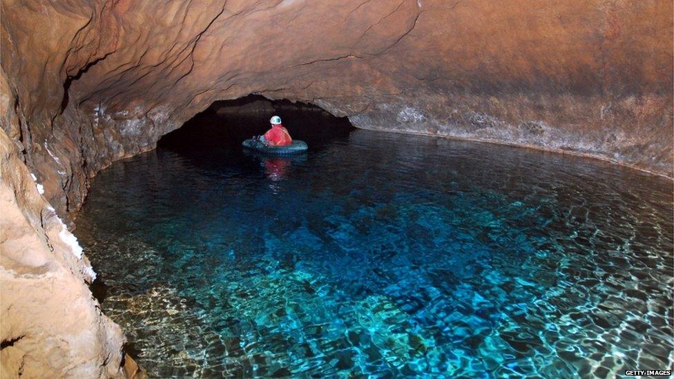 A spelunker on a boat inside the cave