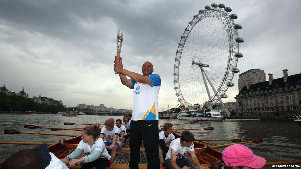 Baton-bearer Brian Dickens holds the Queen's Baton on board the Gloriana as it makes its way down the River Thames on 7 June 2014