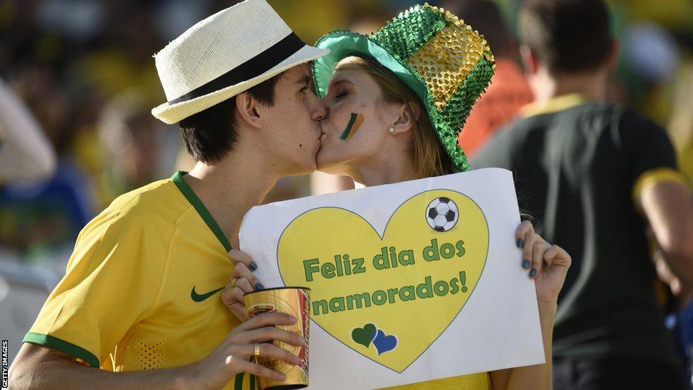 Brazilian fans embrace and hold a sign that reads "Happy day of lovers" before the World Cup opener between Brazil and Croatia at the Arena de Sao Paulo