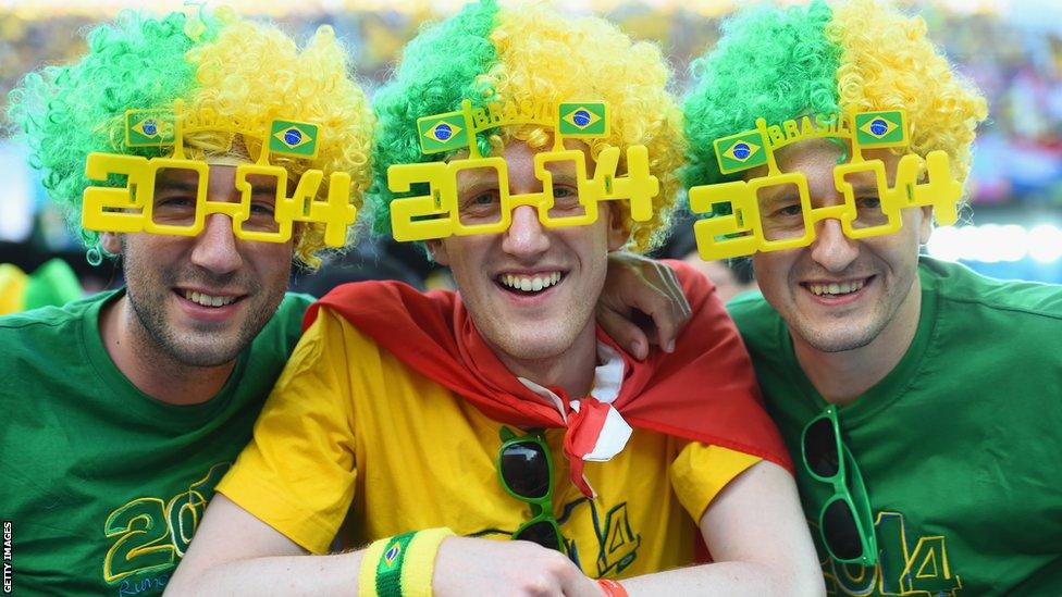 Fans in 2014 shaped glasses pose in the stands at the Arena de Sao Paulo ahead of the World Cup opener between Brazil and Croatia