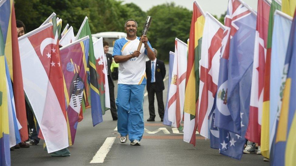 Daley Thompson carrying the Glasgow 2014 Queen's Baton across the bridge at Coldstream from England towards Scotland.