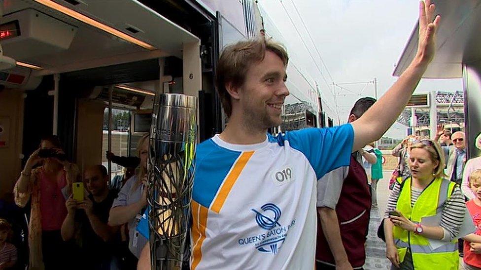 Scottish hockey player Allan Dick boards a tram with the baton at Murrayfield stadium