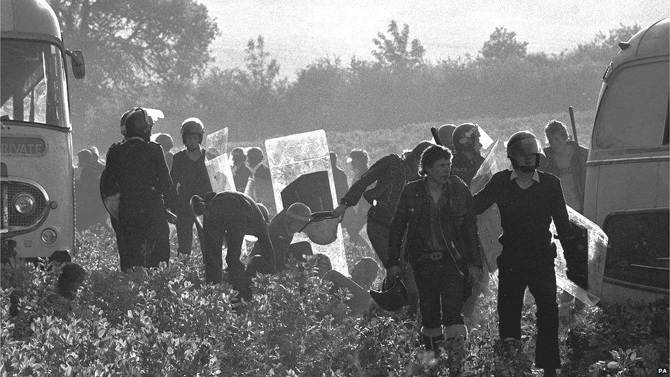 Police officers wearing protective helmets and carrying riot shields and truncheons round up hippies who had tried to fight their way through police to hold an illegal music festival at Stonehenge in 1985