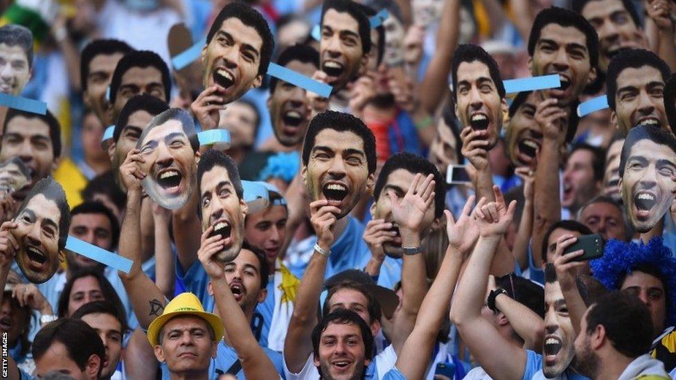 Uruguay fans hold up and wear Luis Suarez masks ahead of the World Cup match against Colombia