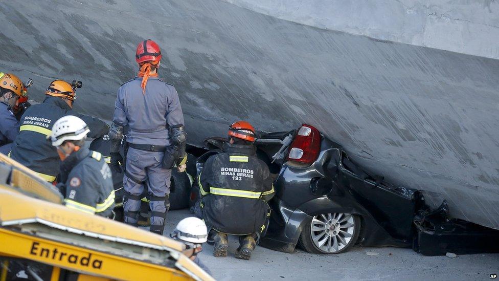 Fire department personnel work to retrieve a car from underneath a collapsed bridge in Belo Horizonte, Brazil, on 3 July2014.