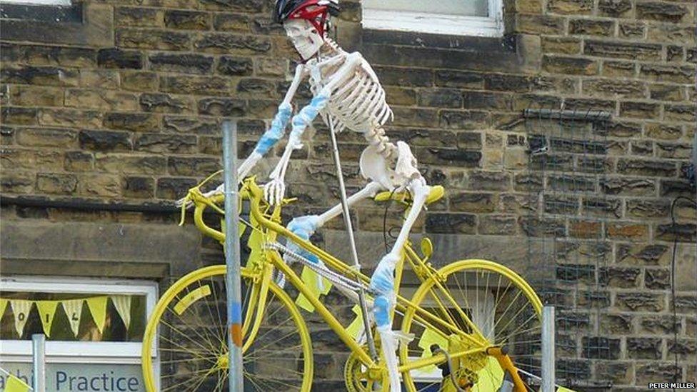 Skeleton on a yellow bicycle.