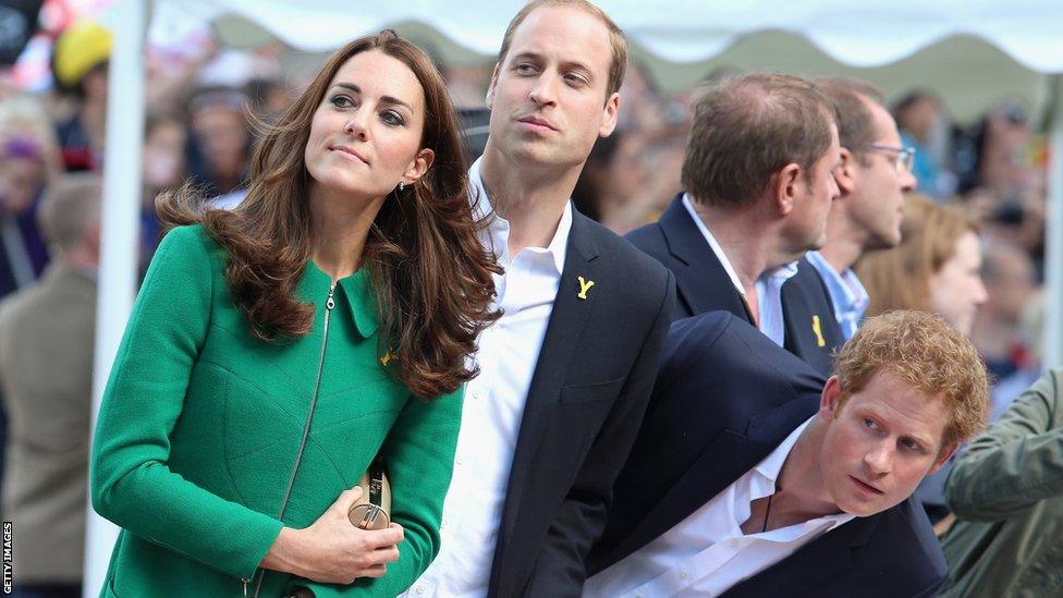 The Duke and Duchess of Cambridge and Prince Harry try to get a glimpse of the riders as they head for the finish line