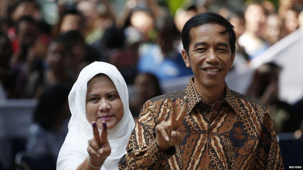 Indonesian presidential candidate Joko Widodo and his wife Iriana pose for pictures after casting their vote in Jakarta on 9 July, 2014