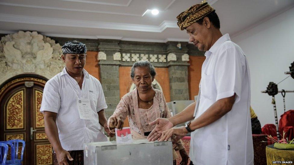 Election officers help a woman to cast her ballot during the Indonesia presidential election on 9 July, 2014 in Denpasar, Indonesia