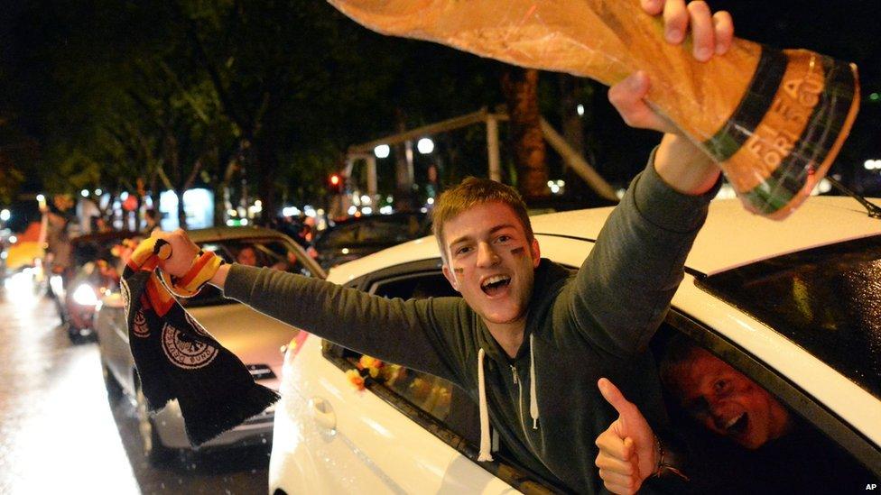 Football fans celebrate with a mock World Cup trophy in Duesseldorf, western Germany,on 8 July 2014