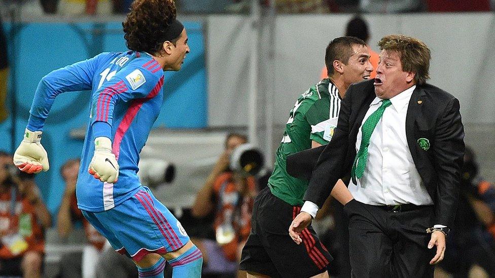 Mexico's goalkeeper Guillermo Ochoa (L) and Mexico's coach Miguel Herrera (R) celebrate a goal by their team during a Group A football match between Croatia and Mexico at the Pernambuco Arena in Recife