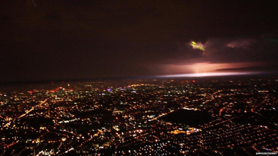 London at night as seen from a helicopter - with a lightning strike in the distance