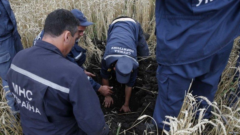 Members of the Ukrainian Emergency Ministry search for bodies near the site of Thursday's Malaysia Airlines Boeing 777 plane crash (18 July 2014)