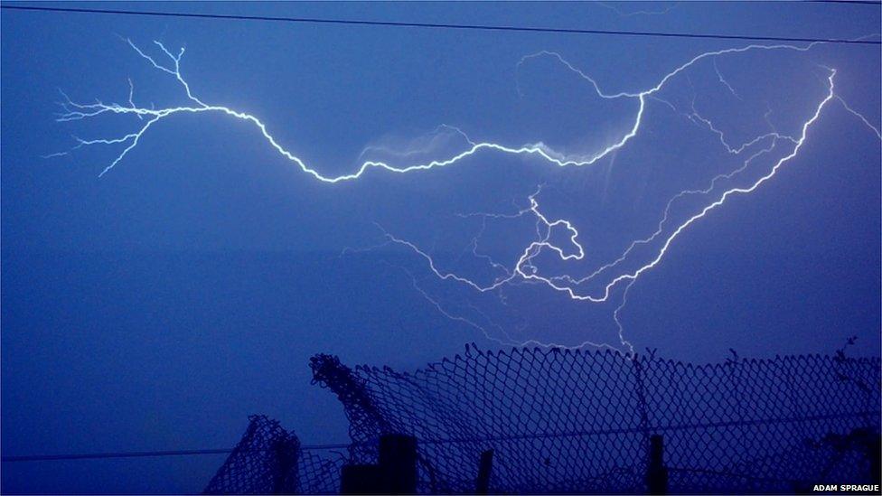 A lightning strike. A wire fence can be seen in the foreground