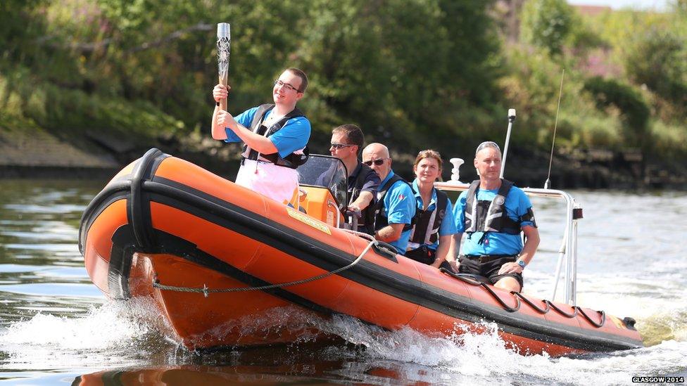 Baton bearer Jordan Robertson carries the Glasgow 2014 Queen's Baton on a boat on the River Clyde in Glasgow.